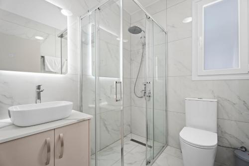 a bathroom with a shower and a toilet and a sink at Oasis Luxury Escape in Xylophaghou