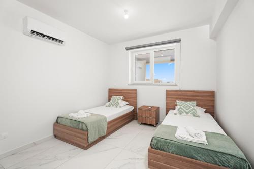 a bedroom with two beds and a window at Oasis Luxury Escape in Xylophaghou