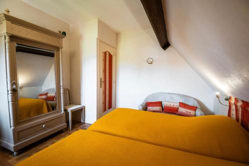 a bedroom with a yellow bed and a mirror at Chambres d'hôtes à Bavent in Bavent