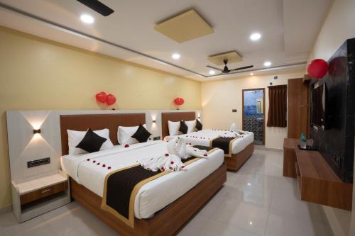 two beds in a hotel room with a flat screen tv at RMA Joliday Inn in Pondicherry