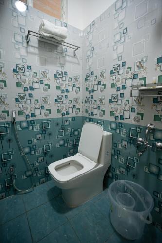a bathroom with a toilet and a green and white wall at RMA Joliday Inn in Pondicherry