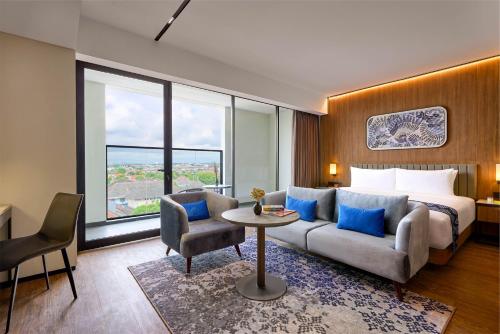 a hotel room with a bed and a couch and a table at Oakwood Yogyakarta in Yogyakarta