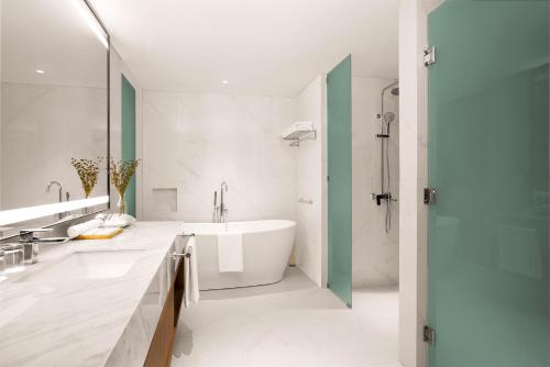 a white bathroom with a tub and a shower at Oakwood Yogyakarta in Yogyakarta