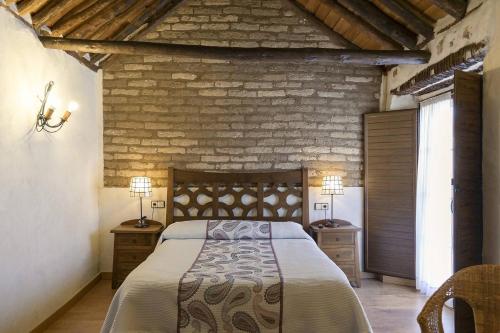 a bedroom with a large bed and a brick wall at Casa Rural Abuelo Pedro in Cuerva
