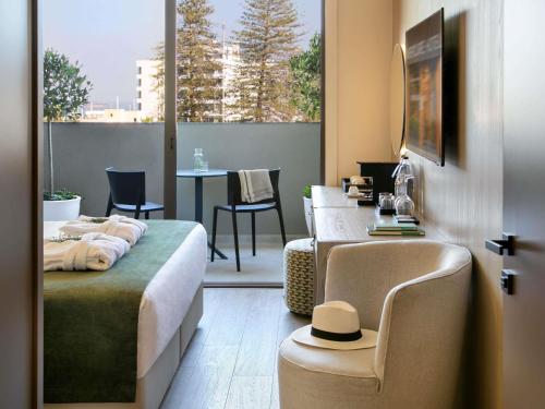 a bedroom with a bed and a table with a hat on it at Mercure Larnaca Finikoudes Beach in Larnaca