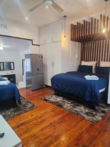 a bedroom with a blue bed and a refrigerator at Ludiz Self Catering Guest House in Avondale