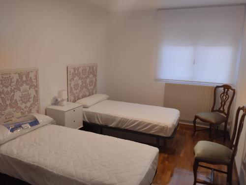 a room with two beds and a chair and a window at Eclipse in Olvega