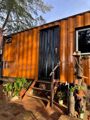 a tiny house with a black door and some plants at Beach hut cabin in Marang