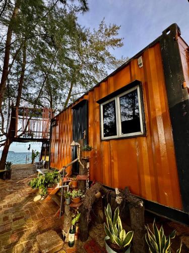 an orange tiny house with a window in a yard at Beach hut cabin in Marang