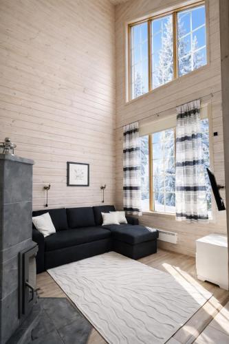 a living room with a black couch and a fireplace at Northern Lights Lodge in Kittilä