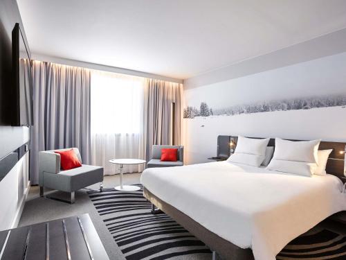 a hotel room with a large bed and a chair at Novotel Lyon Bron in Bron