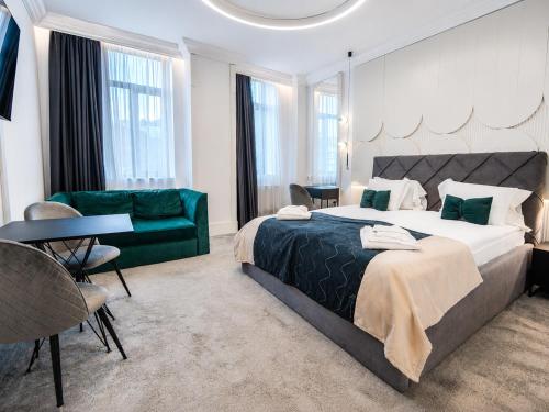 a bedroom with a large bed and a green couch at Tsarevets Boutique Hotel & SPA in Veliko Tŭrnovo