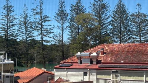 a house with a red roof with trees in the background at Ahoy Brunswick 1 in Brunswick Heads