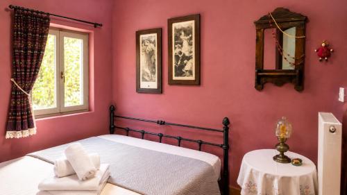 a bedroom with pink walls and a bed and a table at The Blue - Kythira in Kondoliánika