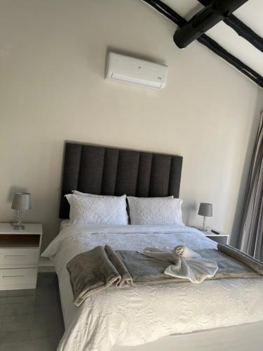 a bedroom with a large bed with a black headboard at Lungi and Rendzo Guesthouse in Alberton