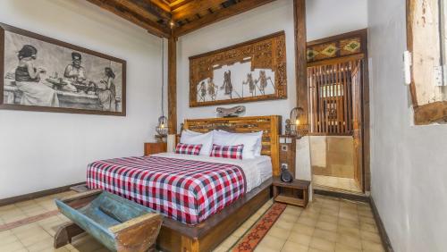a bedroom with a bed with a red and white blanket at The Joglo at Umah Sunset in Ubud