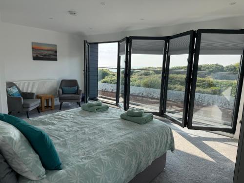 a bedroom with a bed and large glass windows at Fort View- Totland in Totland