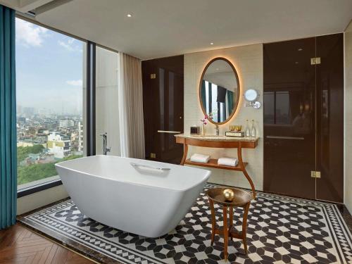 a bathroom with a white tub and a mirror at Grand Mercure Hanoi in Hanoi