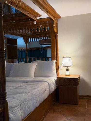 a bed with a wooden frame and a lamp on a table at Kuwait Palace Hotel in Kuwait