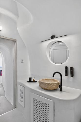 a white bathroom with a sink and a mirror at You and Me Suites Oia in Oia