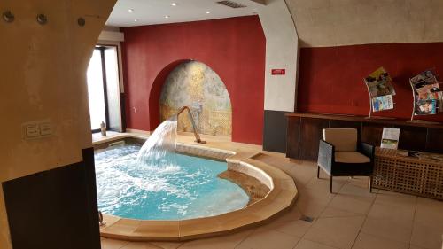 a hot tub with a fountain in a room at Hotel Spa Le Calendal in Arles