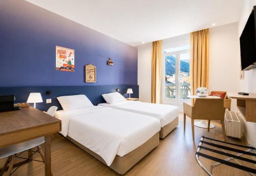 a hotel room with two beds and a desk at B&B HOME Brides-les-Bains Les 3 Vallées in Brides-les-Bains
