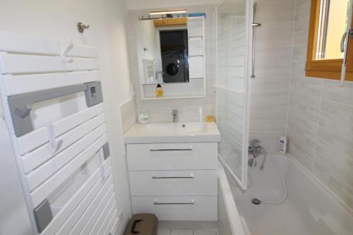 a white bathroom with a sink and a shower at Chalet avec mezzanine 4 étoiles, Saint Mamet, jusqu'à 10 couchages, proche du lac de Gérardmer des commerces et des pistes de ski dans un quartier calme in Gérardmer