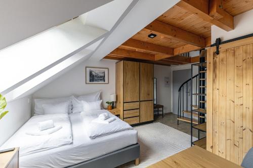 a bedroom with a white bed and a staircase at Stejkárna Špičák in Špičák