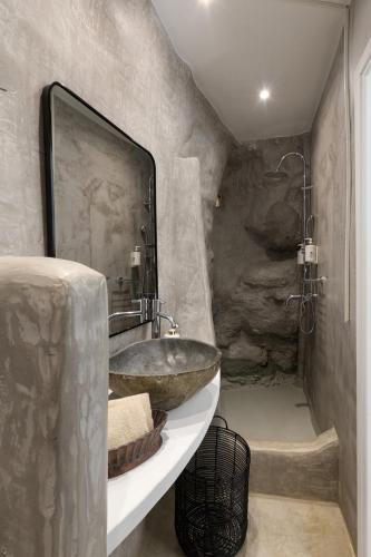 a stone bathroom with a sink and a shower at Domotel Kea in Koundouros