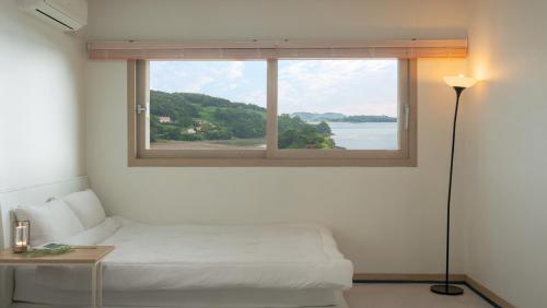 a bedroom with a window with a bed and a lamp at Yeosu Greenhouse Pension in Yeosu