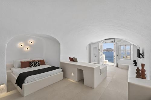 a white bedroom with a bed and a sink at You and Me Suites Oia in Oia