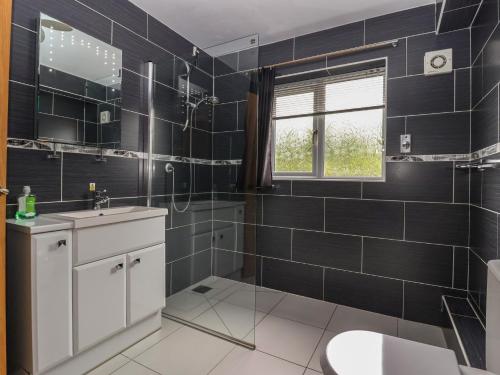 a bathroom with black tiles and a sink and a toilet at Lillieput Lodge in Melbourne
