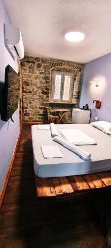 a bedroom with a white bed with a brick wall at Palazzo Gabela in Risan