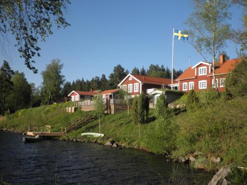 a river with houses on a hill next to a river at Sjöanäs 3 in Tolg