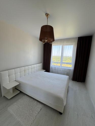 a bedroom with a white bed and a window at Panorama Apartment in Lviv