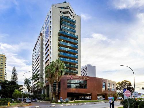 a tall building with a palm tree in front of it at Grand Mercure Brasilia Eixo Monumental in Brasília