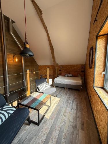 a room with two beds and a couch and a table at Odyssée - Chambre d'hôtes avec sauna privatifs, spa et filet suspendu in Zeggers-Cappel