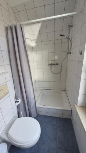 a bathroom with a shower and a toilet and a tub at Goode Wind in Norden