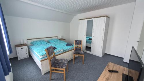 a bedroom with a bed and two chairs and a mirror at Goode Wind in Norden