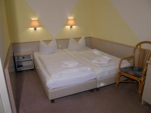 a small bedroom with a white bed and a chair at KA&KA Hotel Garni in Warsow