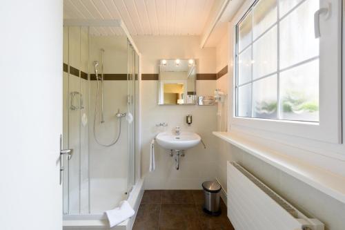 a white bathroom with a sink and a shower at Hotel du Léman - Jongny in Vevey