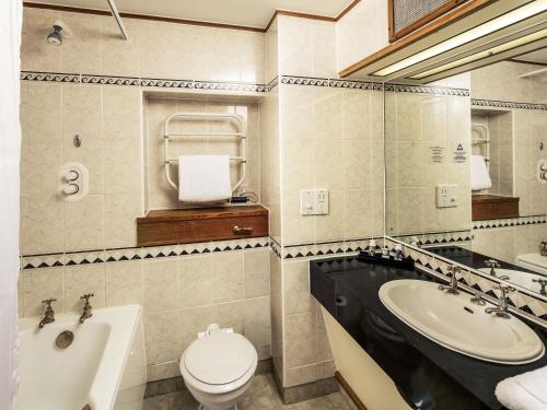 a bathroom with a sink and a toilet and a tub at Mercure York Fairfield Manor Hotel in York