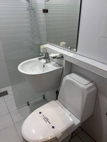 a bathroom with a sink and a toilet and a mirror at Regency Sunset Condotel in Angeles