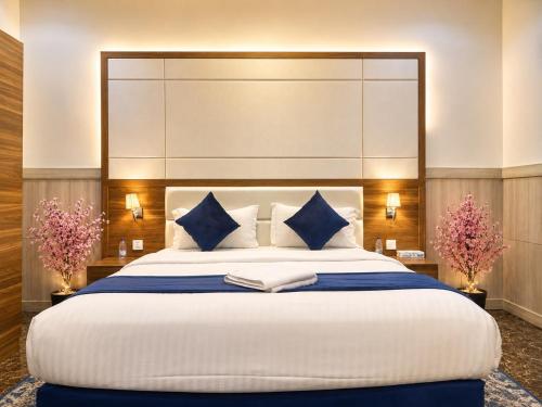 a bedroom with a large bed with blue and white pillows at توارن للشقق المخدومة - الاقتصادية in Riyadh