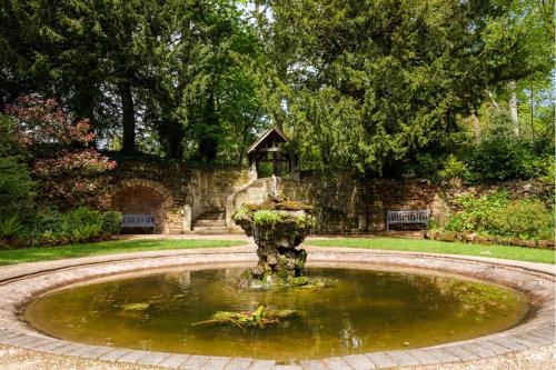a fountain in the middle of a park with a bench at Birmingham North Moor Hall Hotel BW Premier Collection in Sutton Coldfield