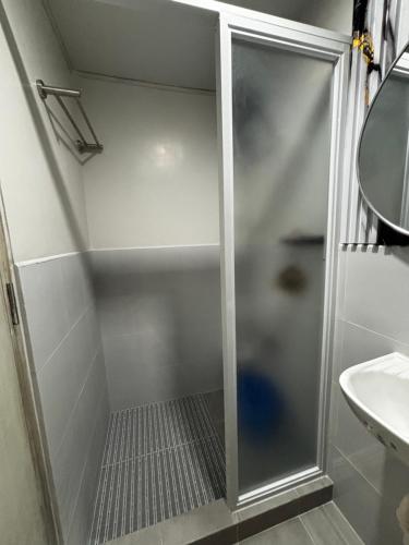 a shower with a glass door next to a sink at Plumera Mactan Bldg A 108 in Bankal