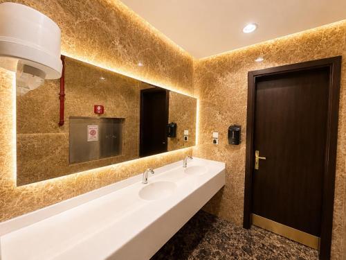 a bathroom with two sinks and a large mirror at توارن للشقق المخدومة - الاقتصادية in Riyadh