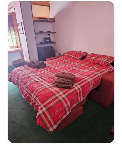 a bed with a red plaid blanket on it at Appartamento Sestriere in Sestriere