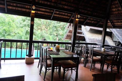 a dining room with tables and chairs and a pool at Sunday Rainforest Chiangmai Hotel in Chiang Mai