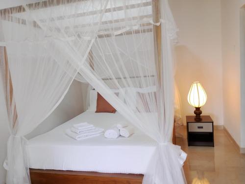 a bedroom with a white bed with a canopy at The White Porch in Kurunegala